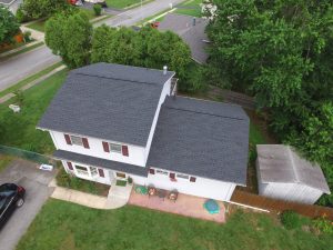 Ana aerial drone image of a modern, two-story home with a new, slate-gray asphalt shingle roof.